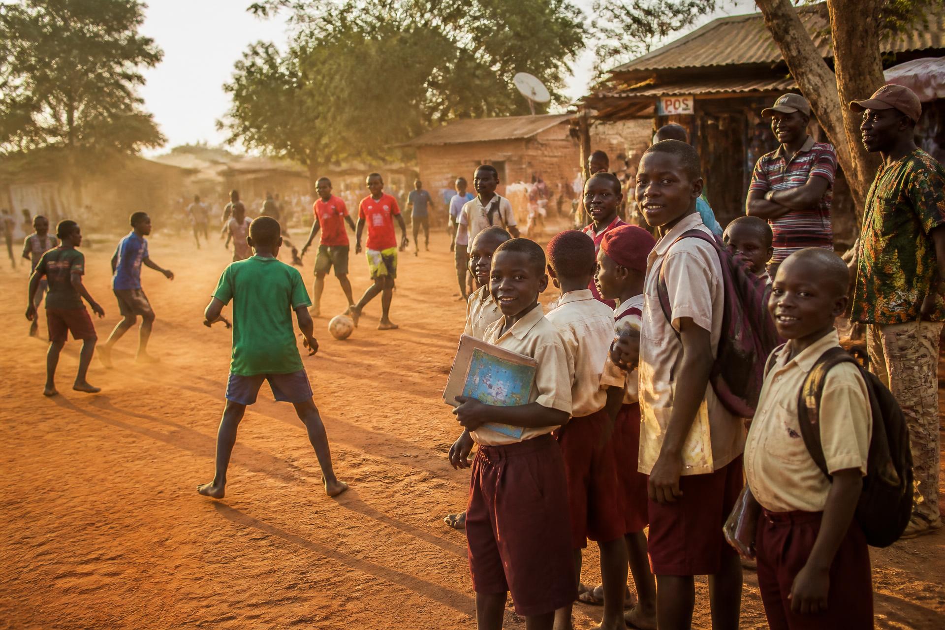 Children in school uniform and young footballers together in a community in Oyo Town, Oyo State, Nigeria